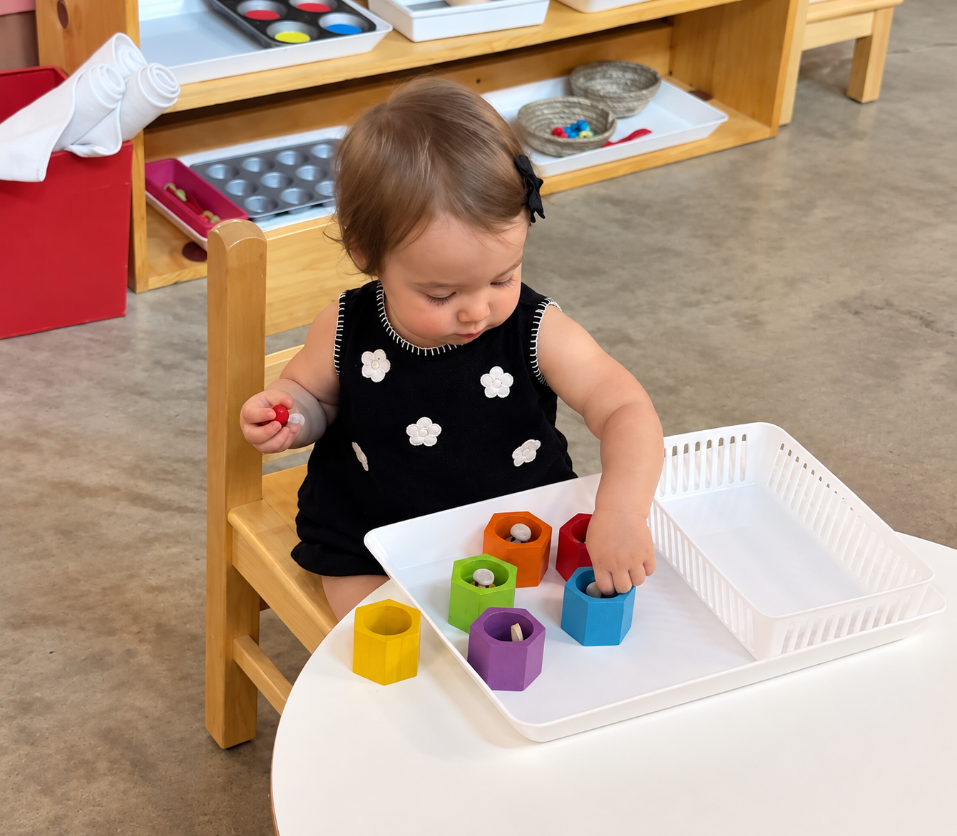 A toddler concentrating on a Montessori counting activity with wooden pegs.