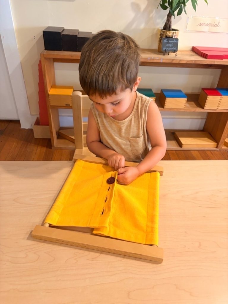 Child practicing an independent Montessori dressing activity at Mi Casita Montessori
