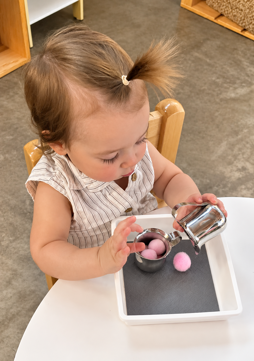 A toddler arranging colorful pieces during a fine-motor classroom activity.